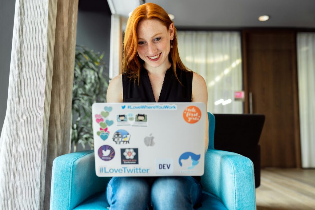 Smiling woman engaged in remote work on a laptop at home office setting.