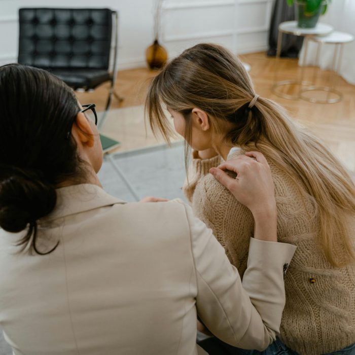 Two women in a moment of support and empathy, indoors sitting together.